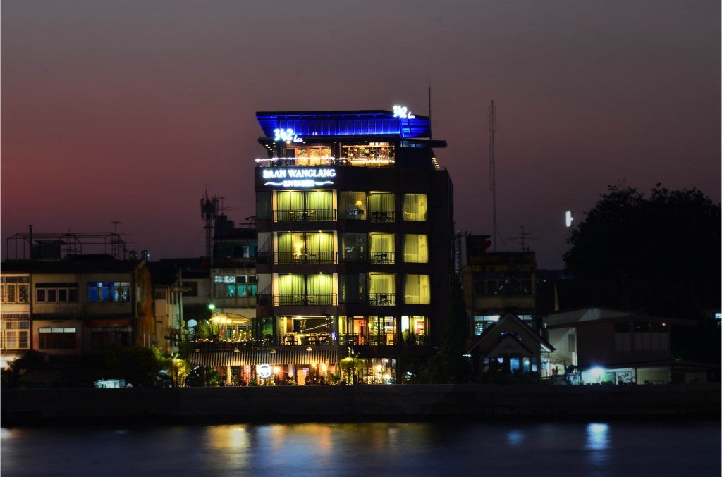 Riverfront hotel exterior at night at Baan Wanglang Riverside