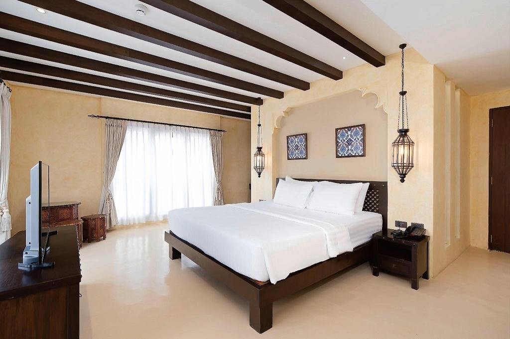 Guest bedroom with ceiling beams at Dewan Bangkok Hotel