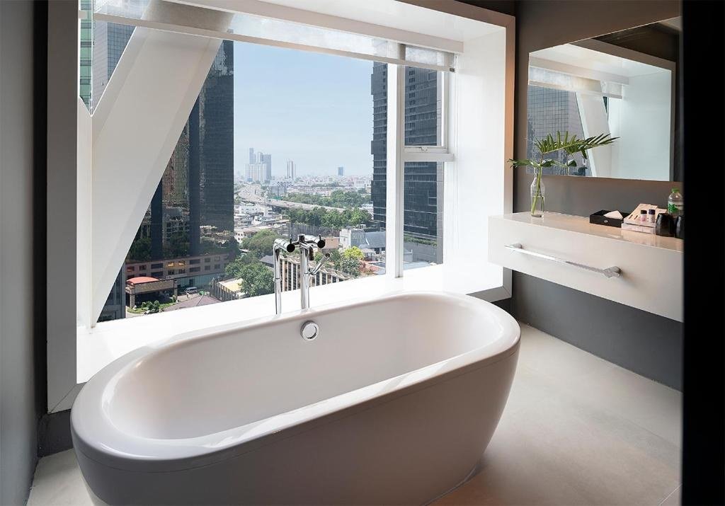 Bathtub beside a city-facing window at Mode Sathorn Hotel