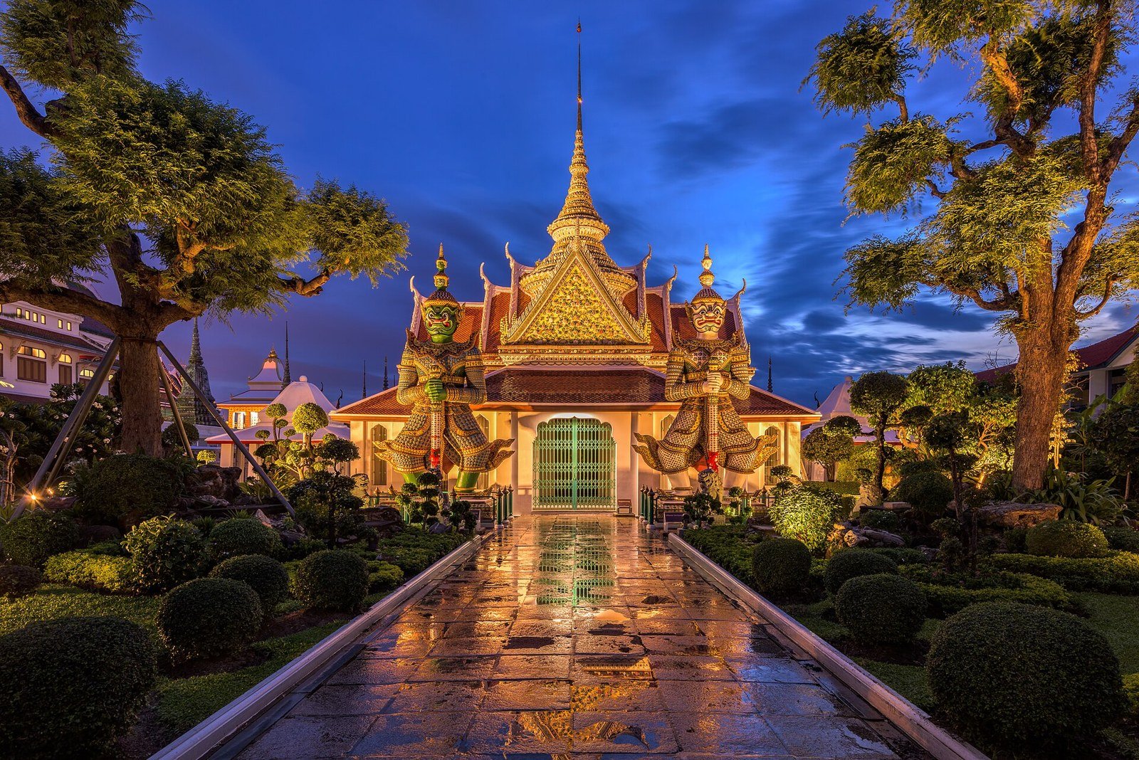 Illuminated gateway and guardian figures at Wat Arun